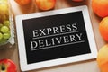 tablet with the words express delivery, oranges, grapes and apples