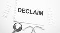 On the tablet for writing the text declaim, next to the stethoscope and white tablets Royalty Free Stock Photo