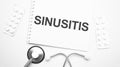 On the tablet for writing the text Sinusitis, next to the stethoscope and white tablets Royalty Free Stock Photo