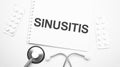 On the tablet for writing the text Sinusitis, next to the stethoscope and white tablets Royalty Free Stock Photo