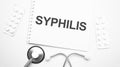 On the tablet for writing the text Syphilis, next to the stethoscope and white tablets