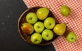 Tabletop photo wood carved bowl with apples and pears, red chequered tablecloth on black board