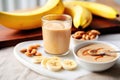 tabletop with smoothie glass, banana and peanut butter spread