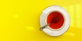 Tabletop view, morning sun shines to white porcelain cup with hot tea, silver spoon in, on yellow board - wide photo Royalty Free Stock Photo