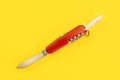 Tabletop view, red pocket knife, with both blades opened, laying on yellow board Royalty Free Stock Photo