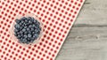 Tabletop view - small bowl of blueberries, with red chequered t Royalty Free Stock Photo