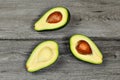 Tabletop view - three halves of cut avocado, some with seed pit, on gray wood desk. Royalty Free Stock Photo