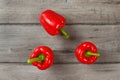 Tabletop view - three red bell peppers on gray wood desk. Royalty Free Stock Photo