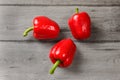 Tabletop view - three red bell peppers on rustic gray wood desk. Royalty Free Stock Photo