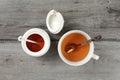 Tabletop view on white porcelain cup with hot tea and silver spoon, honey pot next to it, on gray wood desk. Royalty Free Stock Photo