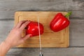 Tabletop view - woman cutting red bell pepper on chopping board Royalty Free Stock Photo