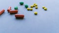 Tablets and caplets on light gray background, yellow, green and orange pills on top left corner of the photo, vitamins