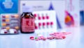 Tablets and capsule pills on blurred drug bottle, capsule in blister pack and paper box package of medicine. Pink and red tablets Royalty Free Stock Photo