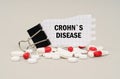 Among the tablets and capsules is a clip with paper on which is written - CROHNS DISEASE