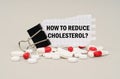 Among the tablets and capsules is a clip with paper on which is written - How to Reduce Cholesterol Royalty Free Stock Photo