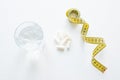 Tablets in capsules, a glass of water and a measuring tape concept diet Royalty Free Stock Photo