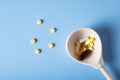 Tablets and capsules are poured into a wooden spoon and on a blue table Royalty Free Stock Photo