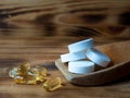 Tablets and capsules in a wooden spoon.