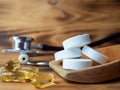 Tablets and capsules in a wooden spoon.