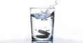 Tablets Falling and Dissolving into a Glass of Water against White Background Royalty Free Stock Photo