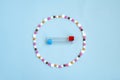 Tablets in the form of a circle inside a test tube for taking a blood sample on a blue background. Royalty Free Stock Photo