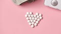 Tablets are laid out in the shape of a heart, blood pressure tonometer with stethoscope on a pink background Royalty Free Stock Photo