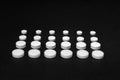 Tablets lined in rows on a black background, different size, close up