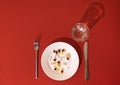 Tablets, pills and capsules on a white porcelain plate. The table is set with a plate, fork, knife and water glass. Red bright Royalty Free Stock Photo