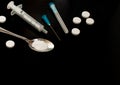 Tablets and syringe on a black background. powder in a spoon. Drugs and the consequences of AIDS