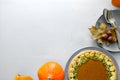 Tableware, homemade pumpkin pie, pumpkin and acorns on gray wooden background. Royalty Free Stock Photo