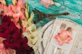 Tableware and silverware with light pink, white and red gladiolus on the azure background Royalty Free Stock Photo