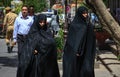 Tabriz, Iran - May 2, 2017: two Iranian women walk along a city street completely hiding in a long black chador. Muslim women with
