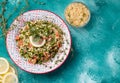 Tabule - an oriental salad, an appetizer on a blue background next to a lemon and bulgur