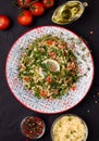 Tabule - an oriental salad, on a black background next to the ingredients