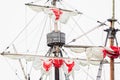 Tackles of an old sailing vessel - a mast, a mast, raised red-white sails, ropes. Royalty Free Stock Photo