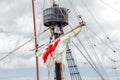 Tackles of an old sailing vessel - a mast, a mast, raised red-white sails, ropes.