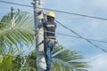 Tacloban, Leyte, Philippines - A lineman installs new wiring while secured on an electric pole with a safety harness