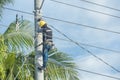 Tacloban, Leyte, Philippines - A lineman installs new wiring while secured on an electric pole with a safety harness