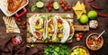 Taco party. Corn tortillas with grilled chicken fillet, salsa sauce, mango, cilantro and red onion on rustic wooden cutting board