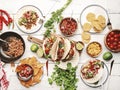 Taco party. Served table with tortillas, nachos, sauces, appetizers and plates. Homemade mexican food cooking scene. White table