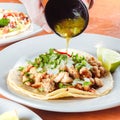 Taco platter with man pouring sauce at a traditional mexican restaurant