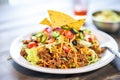 taco salad with ground beef and shredded cheese on top