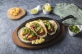 Tacos al pastor accompanied by pineapple, guacamole and spicy sauce served in an iron pan