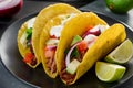 Tacos with slices of lime on black plate. Corn tortilla