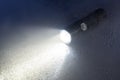 Tactical flashlight on wet surface with beam Royalty Free Stock Photo