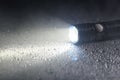 Tactical flashlight on wet surface with beam Royalty Free Stock Photo