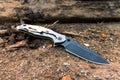 Tactical knife with a black blade on a background of brown wood. Royalty Free Stock Photo