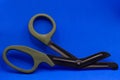 tactical scissors opened on a blue background with dark green handles.