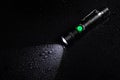 Tactical waterproof flashlight with waterdrops on black background