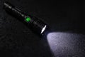 Tactical waterproof flashlight with waterdrops on black background